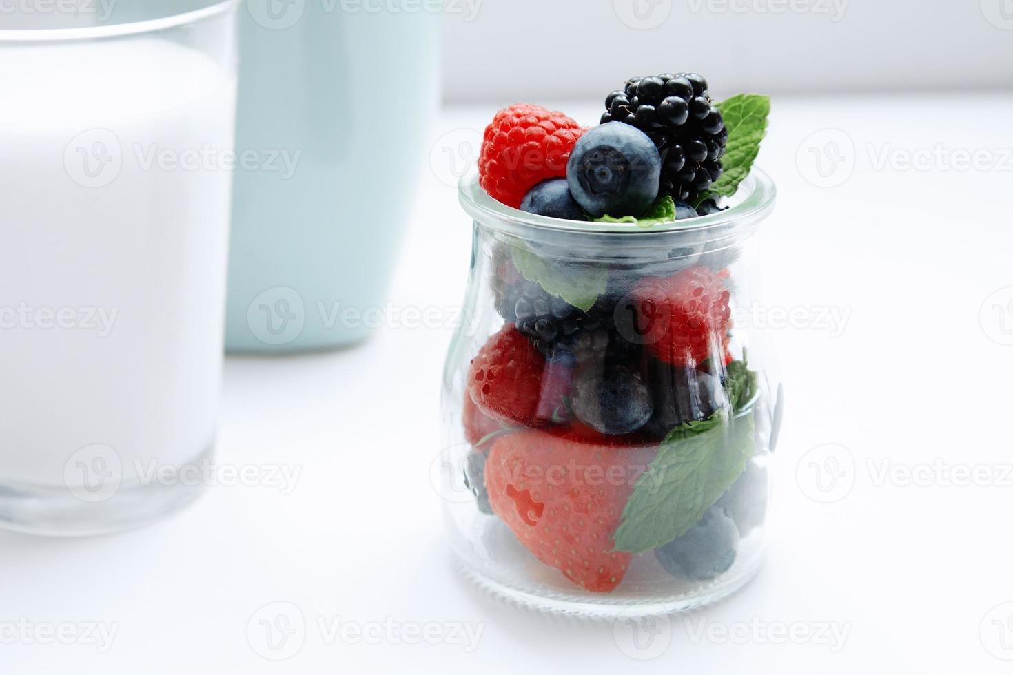frutas e hortelã na jarra e copo de leite foto
