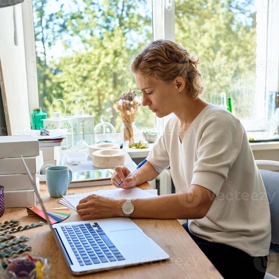 designer de jovem empreendedora escrevendo na folha de papel, mulher séria pensando e planejando foto