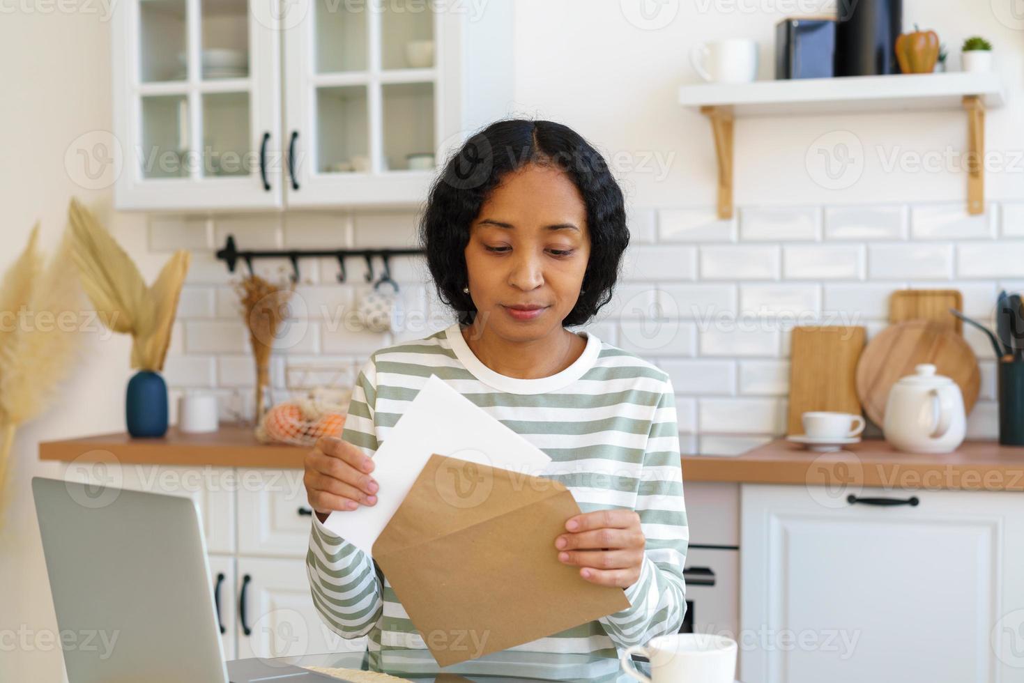 mulher afro-americana enviando carta. preparação de correspondência para entrega de correio. fechamento do envelope foto