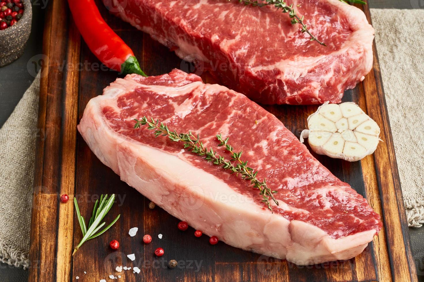 temperar o bife cru com sal, tomilho, alho. dois grandes pedaços inteiros de carne bovina crua foto