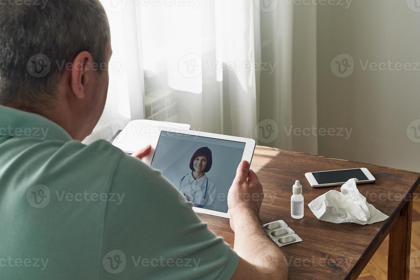 homem olha para tablet, videochamada para médico, comunicação com médico online. telemedicina foto