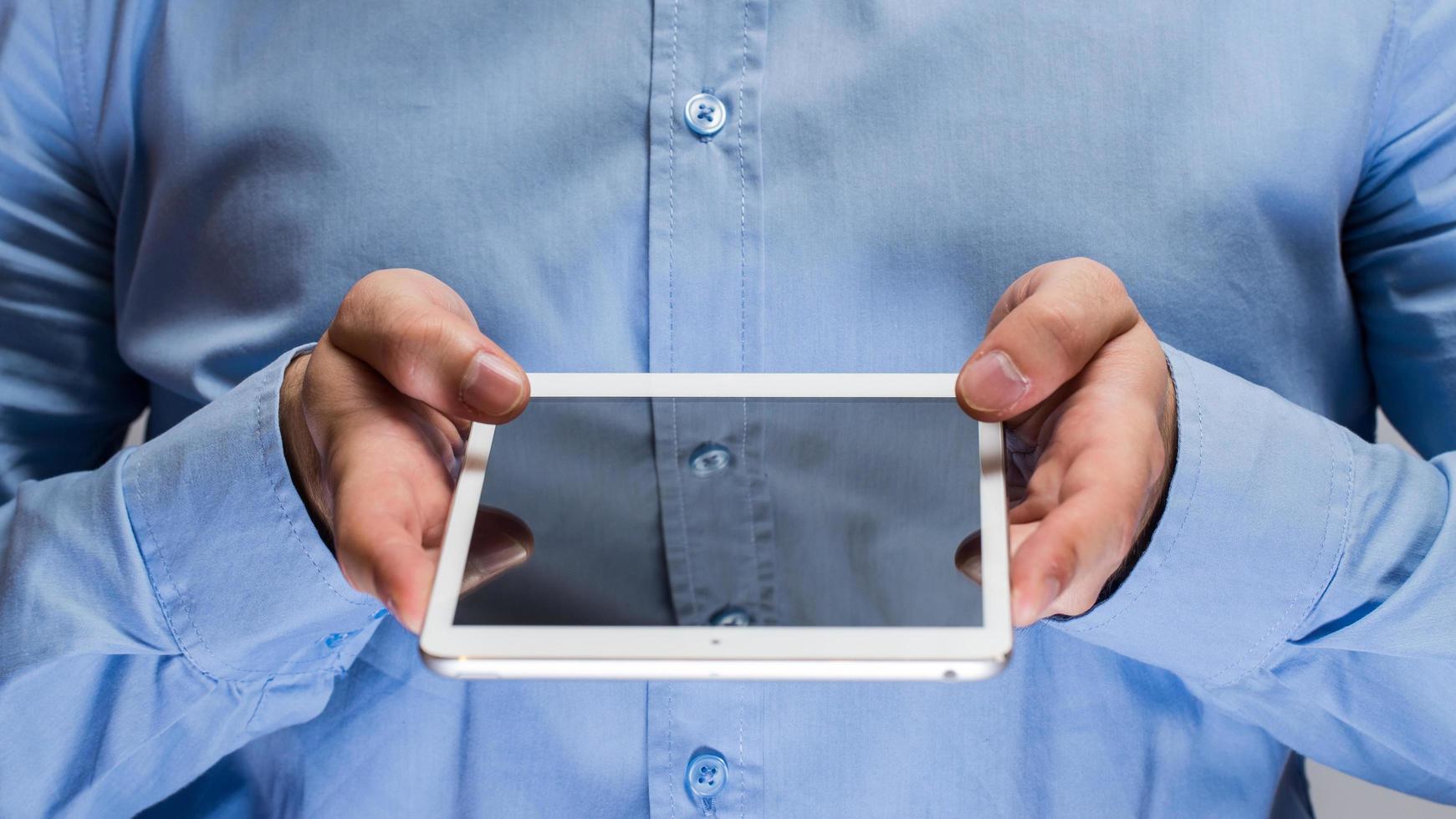 homem de camisa azul segurando o tablet pc branco foto