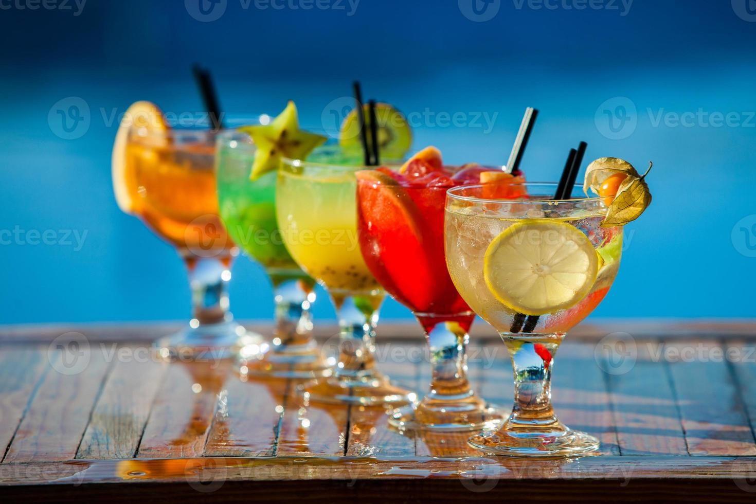 vários coquetéis alcoólicos em fundo branco. coquetéis coloridos fecham. bebida de coquetel de suco de frutas. coquetéis variados. copos de bebidas de frutas com cubos de gelo na mesa no café foto