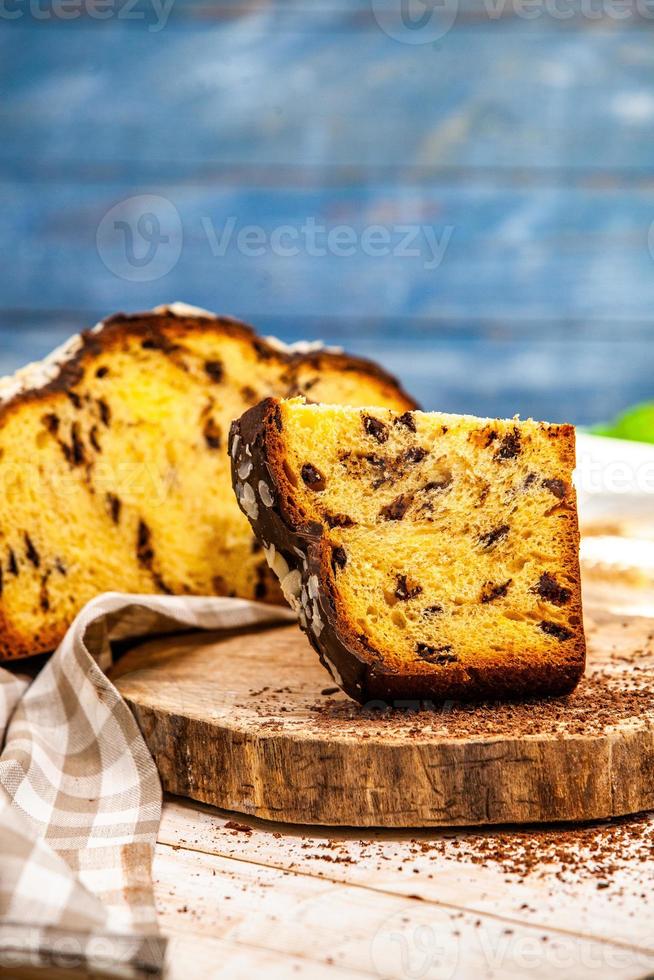 panetone feito em casa. pão doce italiano tradicional. panetone com uma fatia servida em uma mesa de madeira. foto