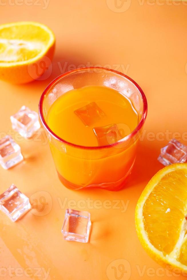 vista superior de um copo de suco de laranja com gelo na cor de fundo foto