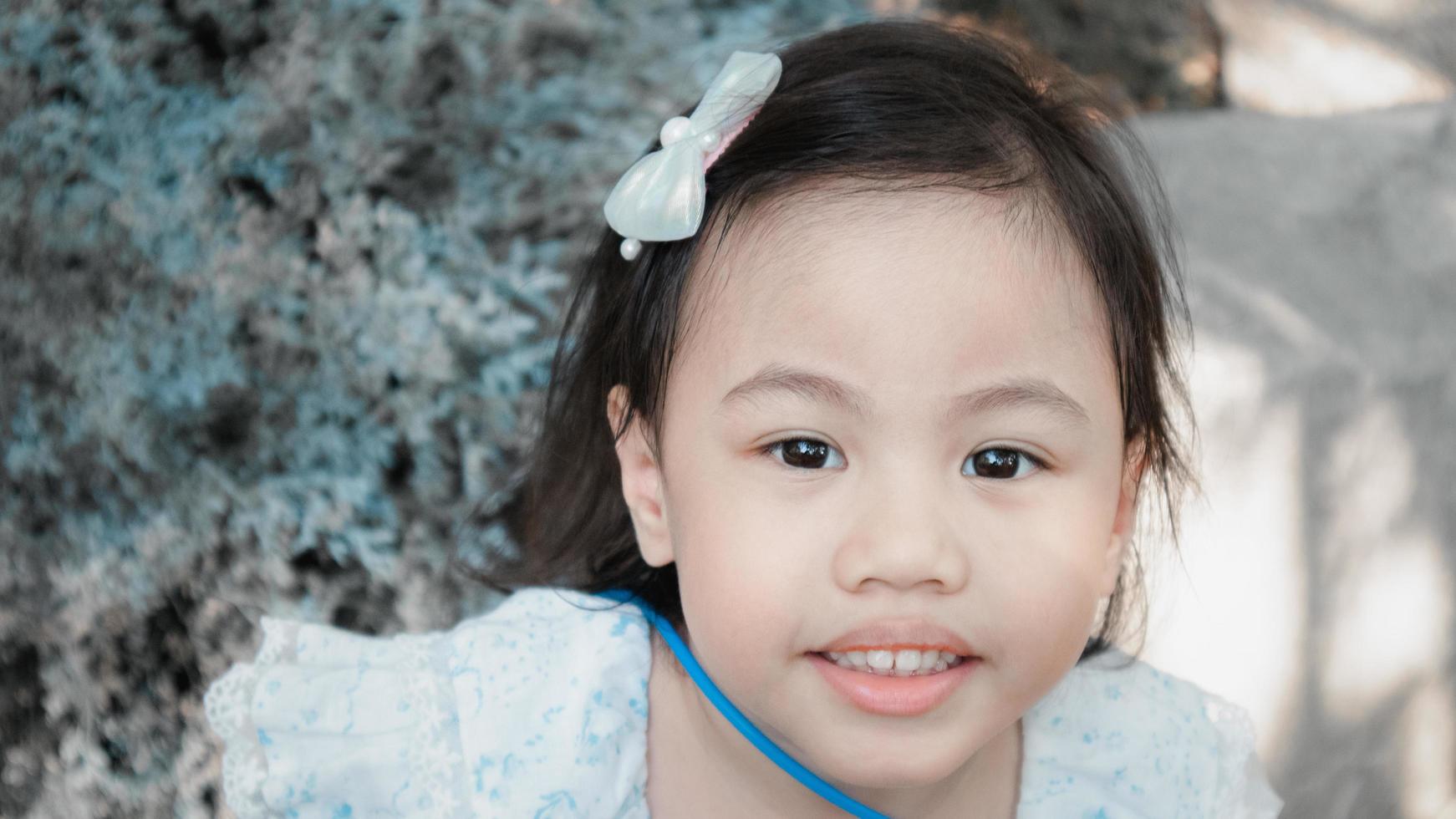 positiva encantadora menina asiática de 4 anos de idade, criança pré-escolar sorrindo e olhando para a câmera foto