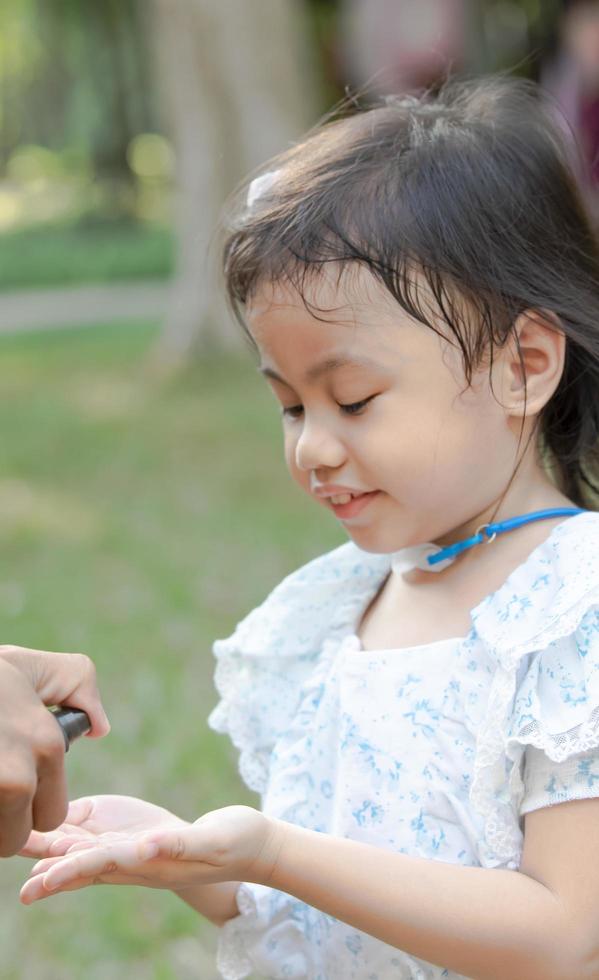 a mão da criança estava encharcada com um spray de álcool, pulverizado por seu pai. evitar a propagação de germes e bactérias e evitar infecções por coronavírus. conceito de higiene infantil foto