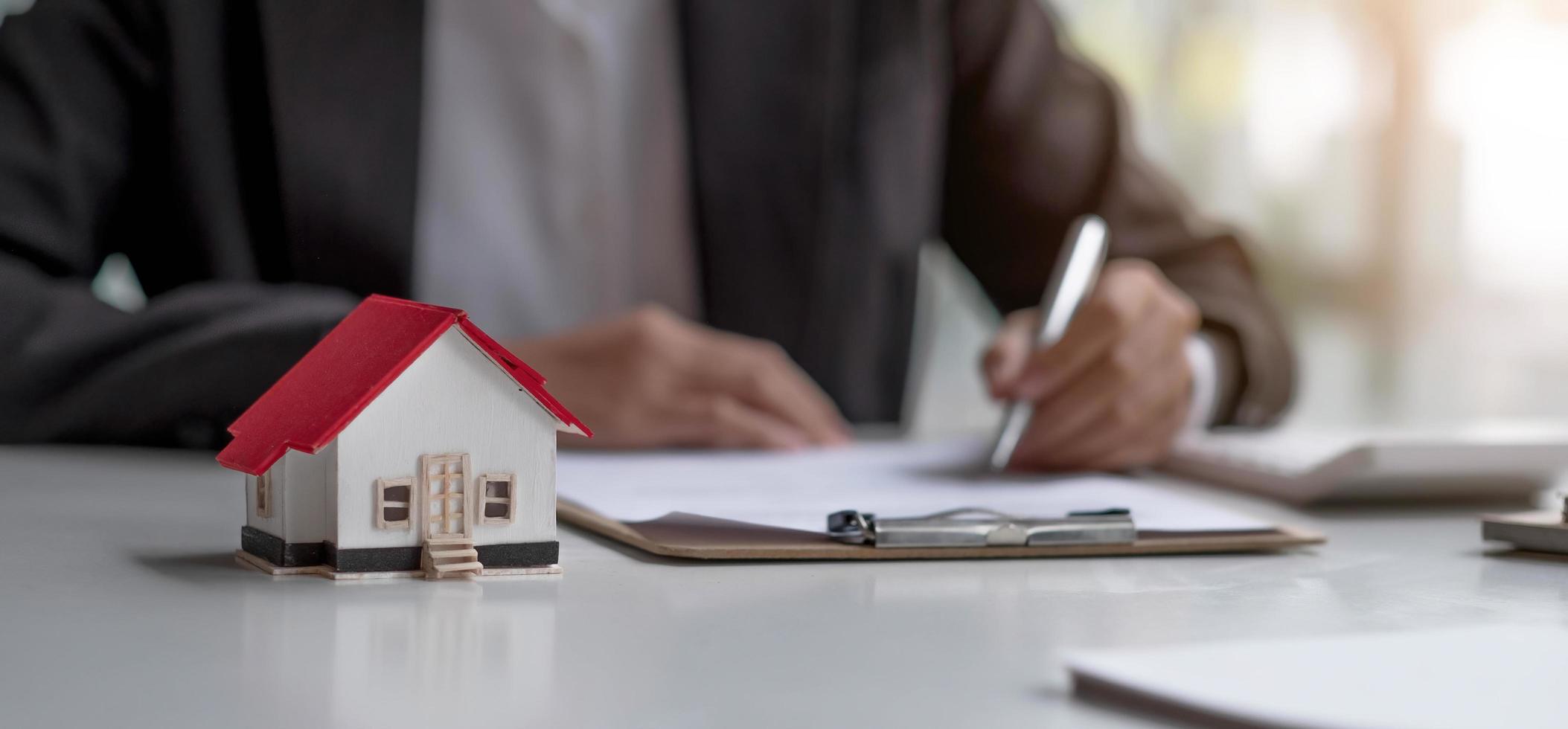 agentes imobiliários trabalham em mesas em salas com papelada e projetos de casas para apresentar os clientes. foto