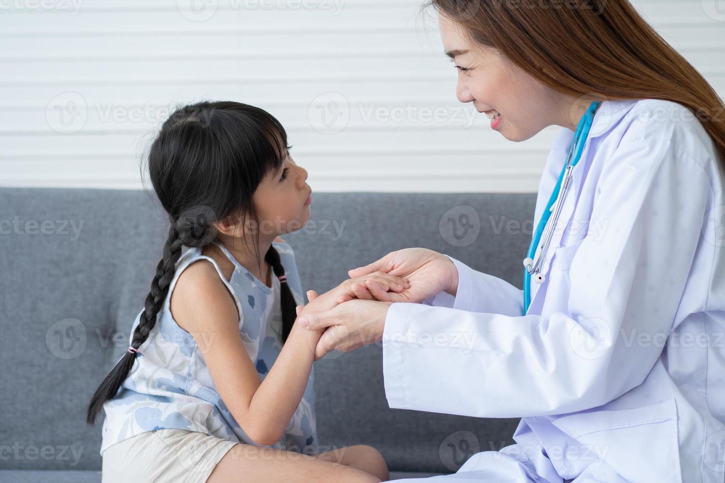 médica pediatra de mulher asiática segura estetoscópio para exame de uma menina paciente e pulmões de coração de criança, bom médico de família visitando criança em casa, saúde e medicina para o conceito de infância. foto