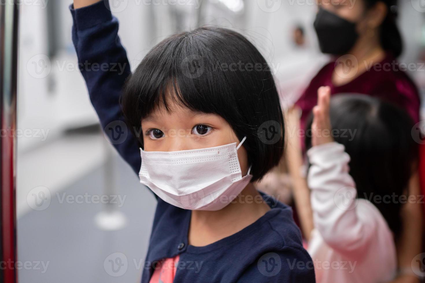 menina com máscara cirúrgica proteção facial contra gripe e surto de vírus em transporte público skytrain ou metrô. conceito de novo estilo de vida normal, usando o transporte público para viajar para a escola. foto