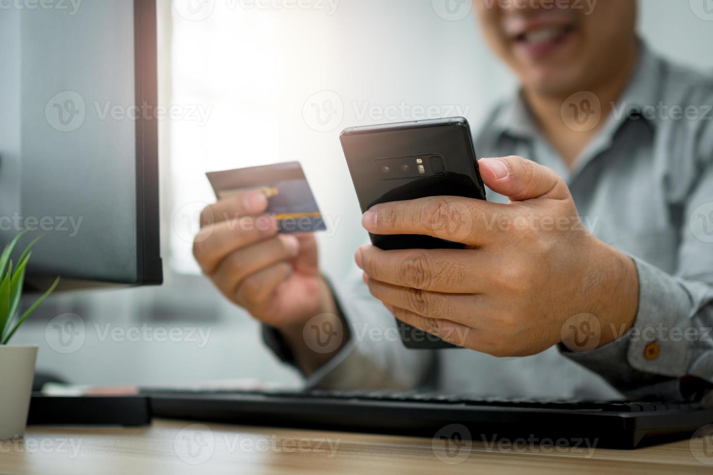 um homem segurando cartão de crédito e usando smartphone para pagamento on-line para compra após o pedido de produtos pela internet. o conceito de tecnologia para comércio eletrônico e-commerce foto