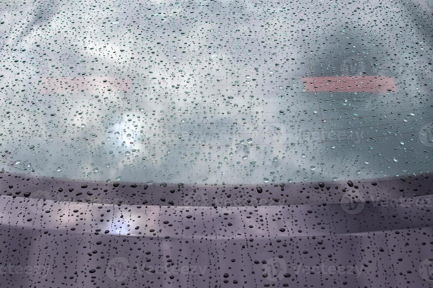 chuva cai em uma superfície de carro metálico preto em uma visão de closeup. foto