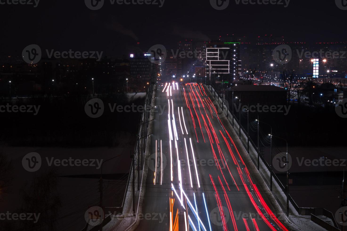 as trilhas de luz do carro na estrada na cidade moderna à noite foto