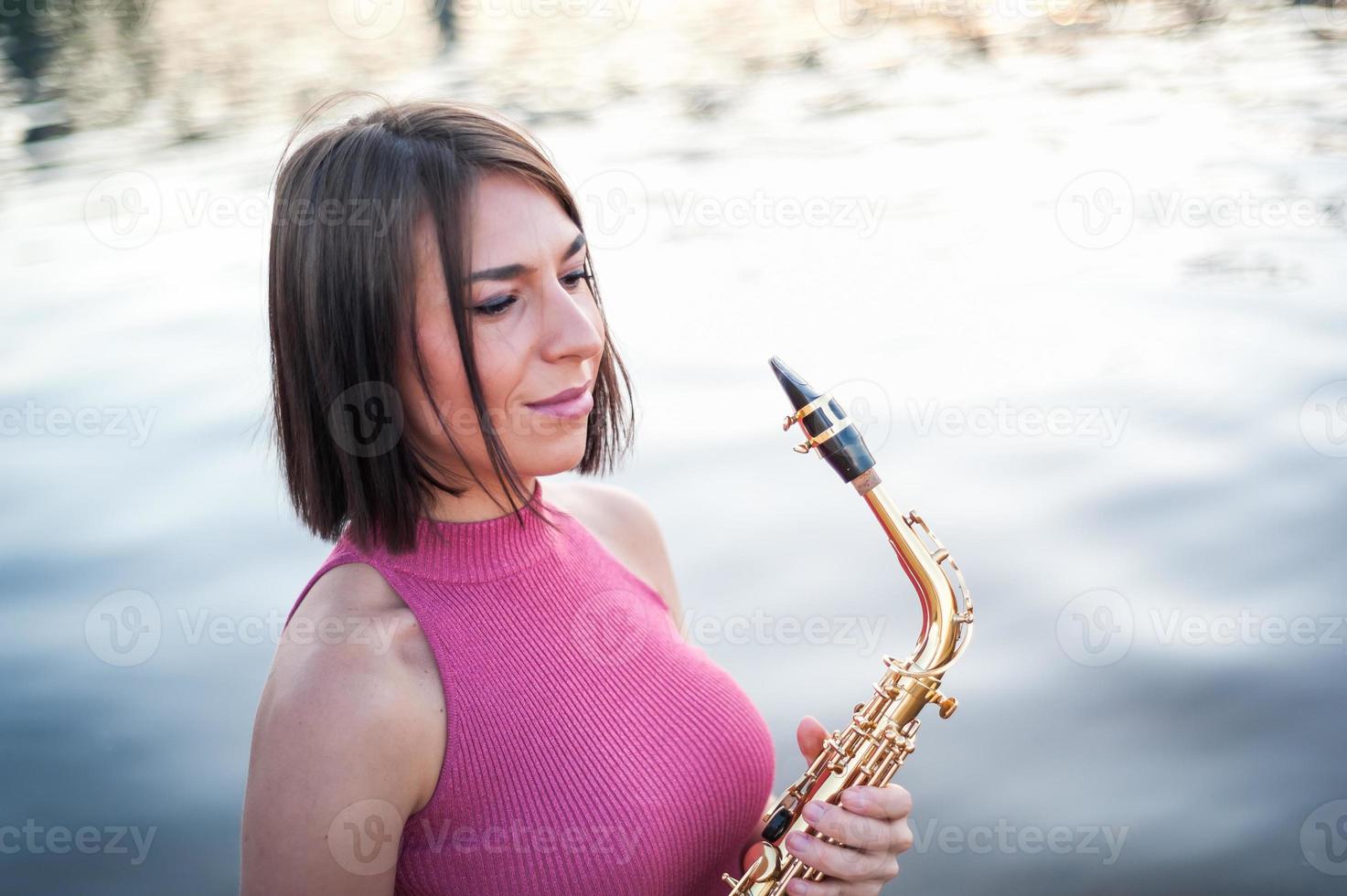 mulher tocando saxofone ao pôr do sol. foto