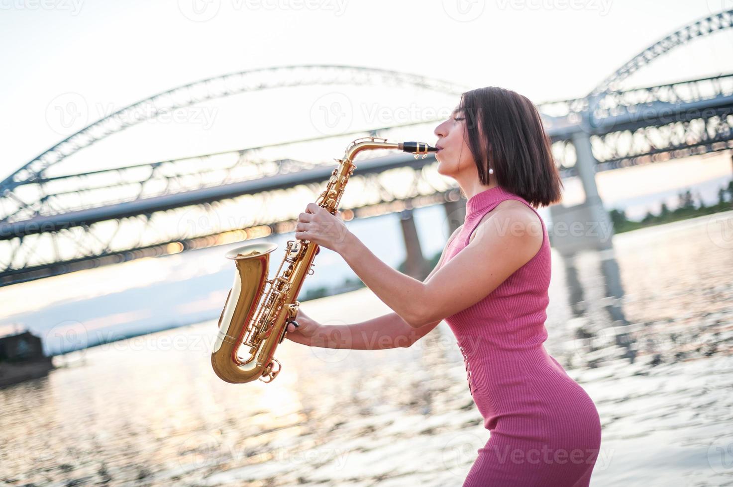 mulher tocando saxofone ao pôr do sol. foto