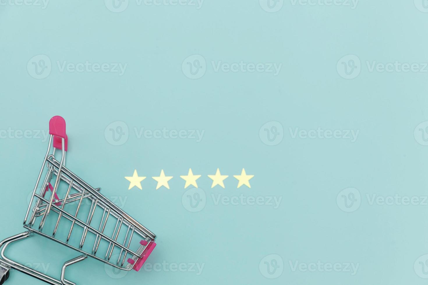 carrinho de supermercado pequeno supermercado para brinquedo de compras com rodas e classificação de 5 estrelas isolado em fundo azul pastel. consumidor de varejo comprando avaliação on-line e conceito de revisão. foto