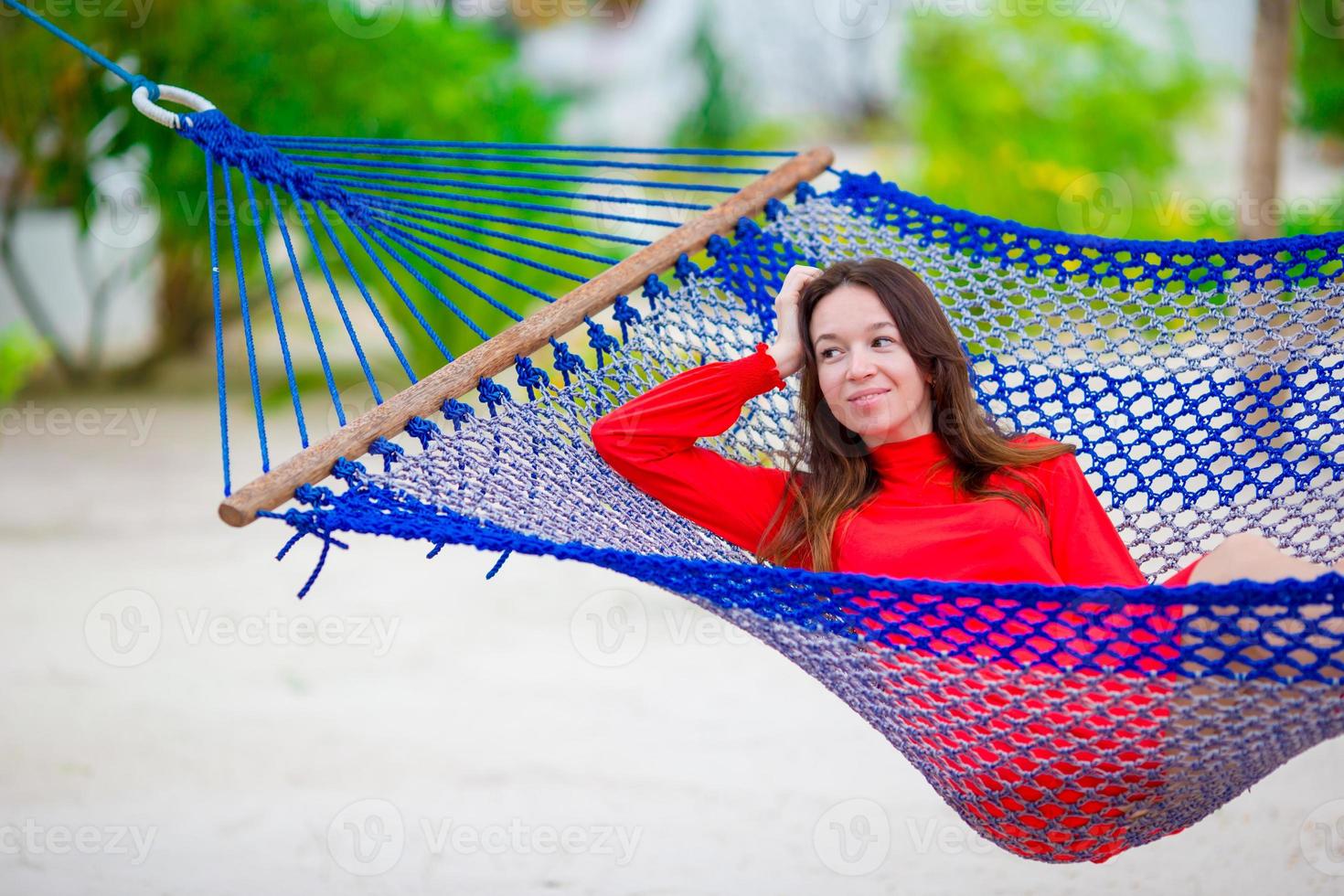 linda mulher relaxante na rede na praia tropical foto