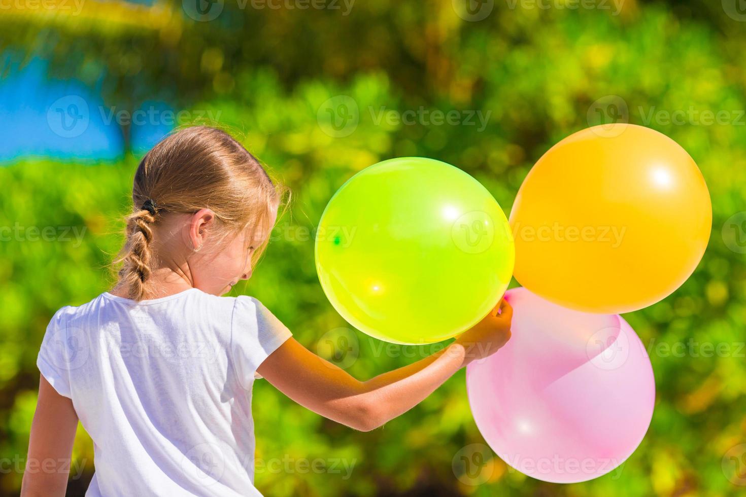 adorável menina brincando com balões na praia foto