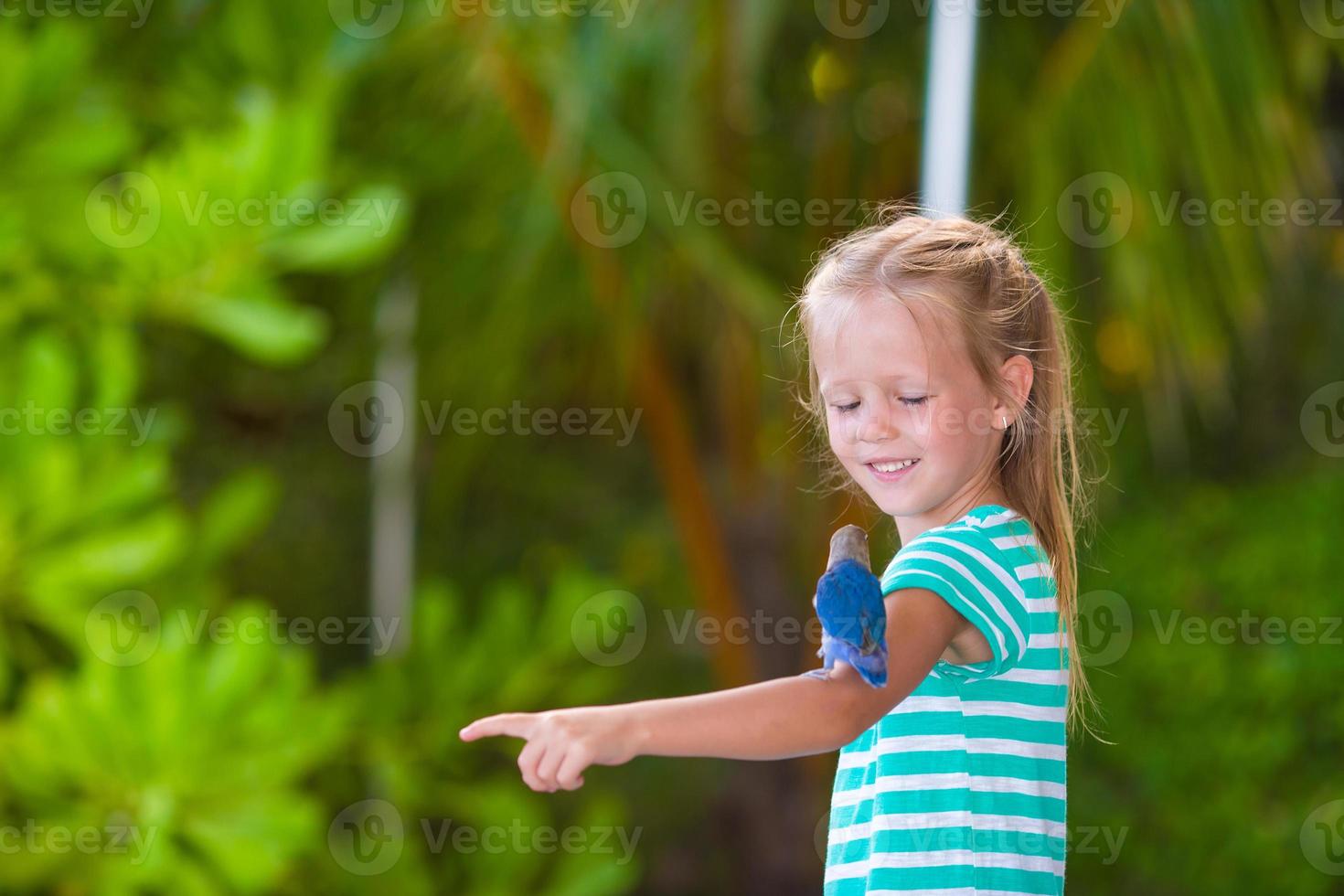 adorável garota feliz na praia com passarinho colorido foto
