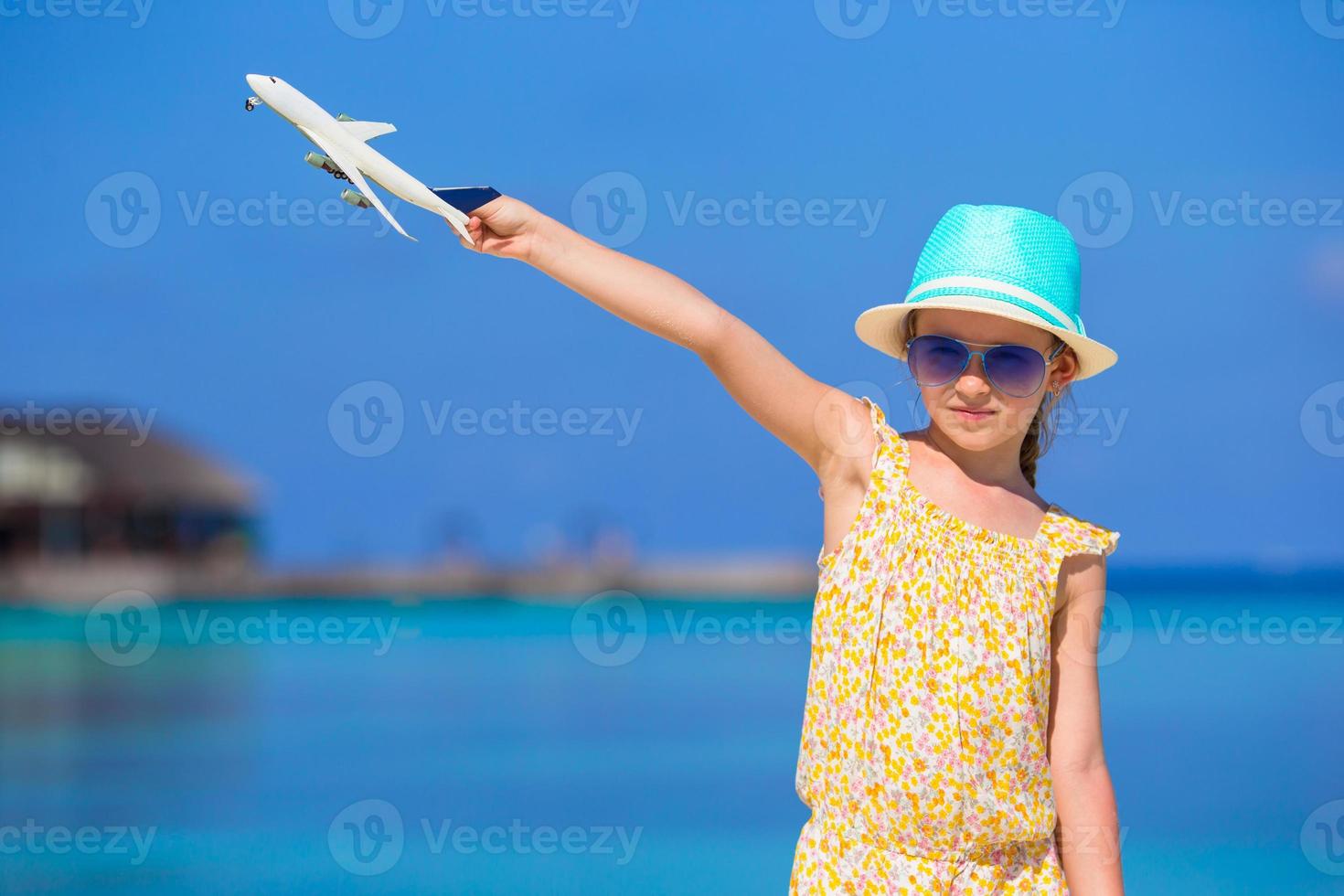 menina feliz com avião de brinquedo nas mãos na praia de areia branca foto