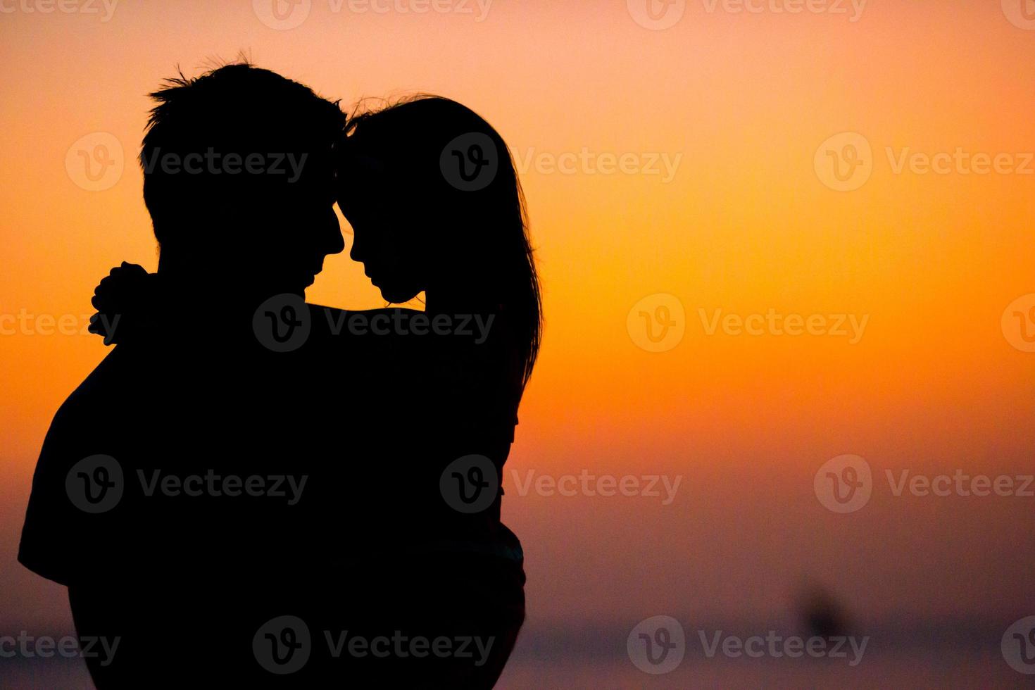 silhueta de menina e pai no pôr do sol na praia foto