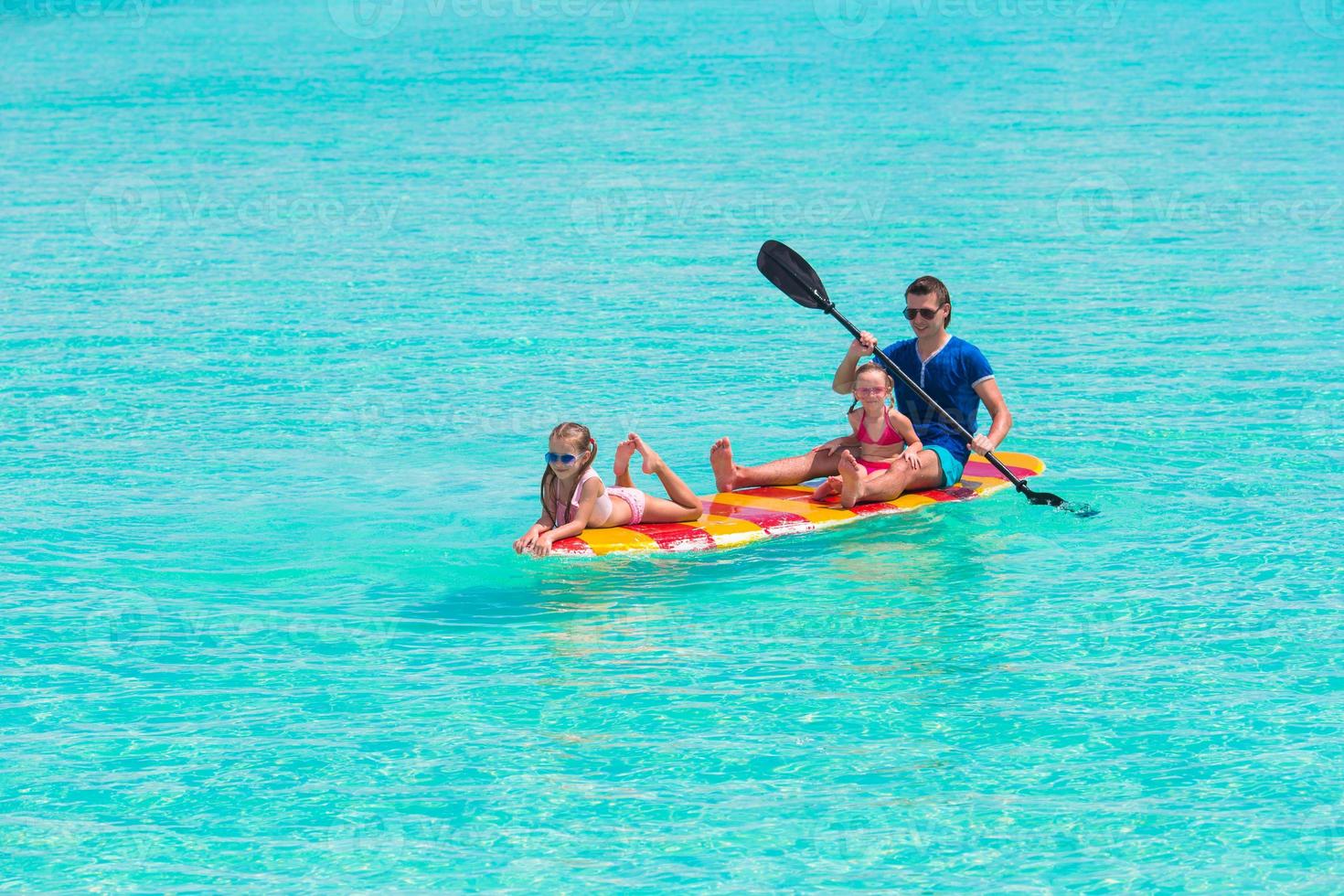 meninas e jovem pai na prancha de surf durante as férias de verão foto