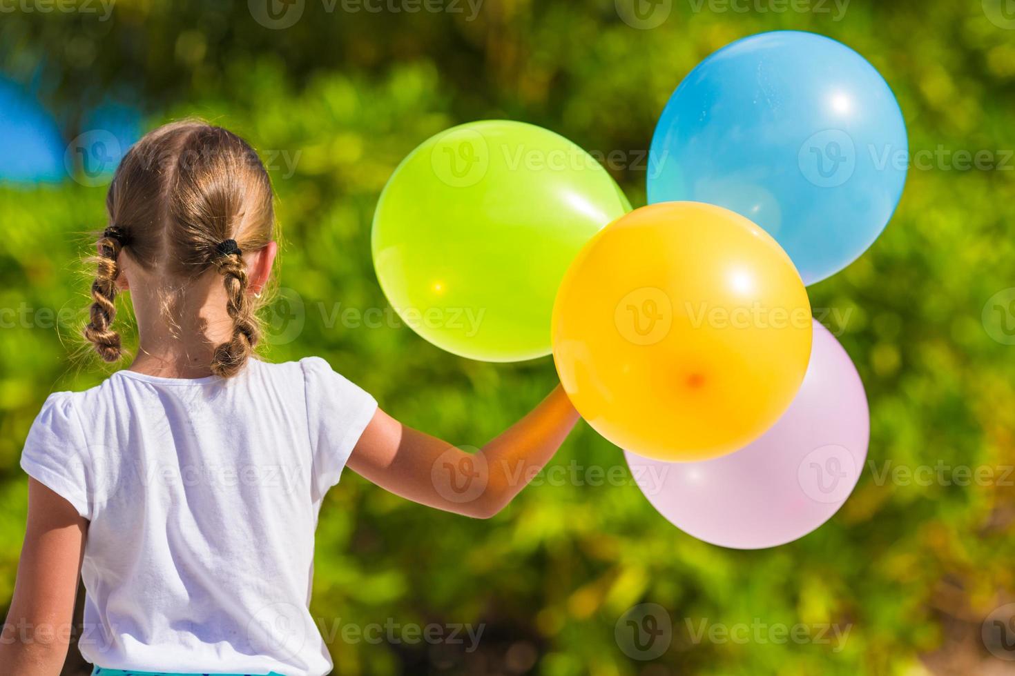 adorável menina brincando com balões na praia foto