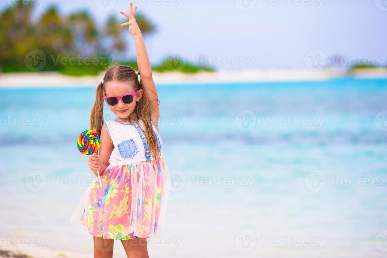 menina adorável se divertir com pirulito na praia foto