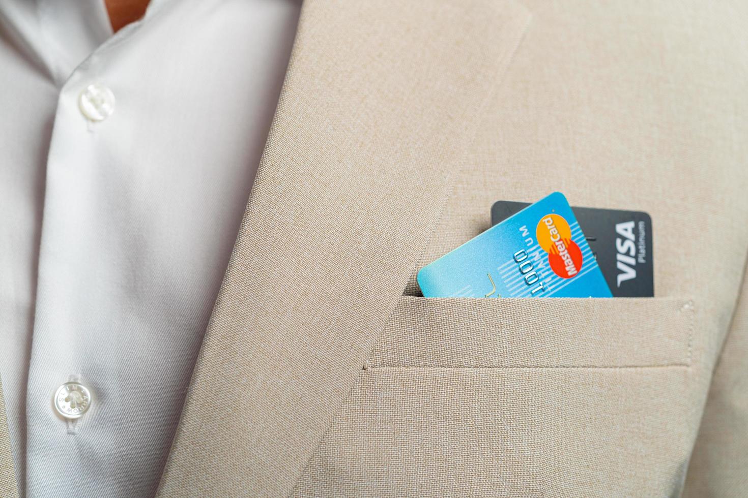 homem de negócios pegar cartões de crédito visa e crédito mastercard com dedos vestindo paletó marrom e detalhes das fibras do belo fundo em 02 21 2022 foto