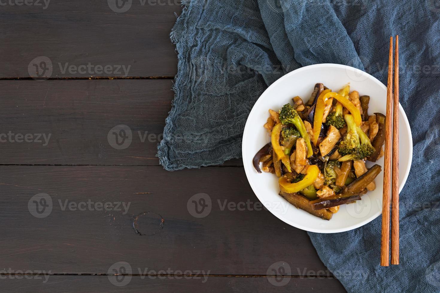 frite frango, brócolis e pimenta em fundo escuro foto