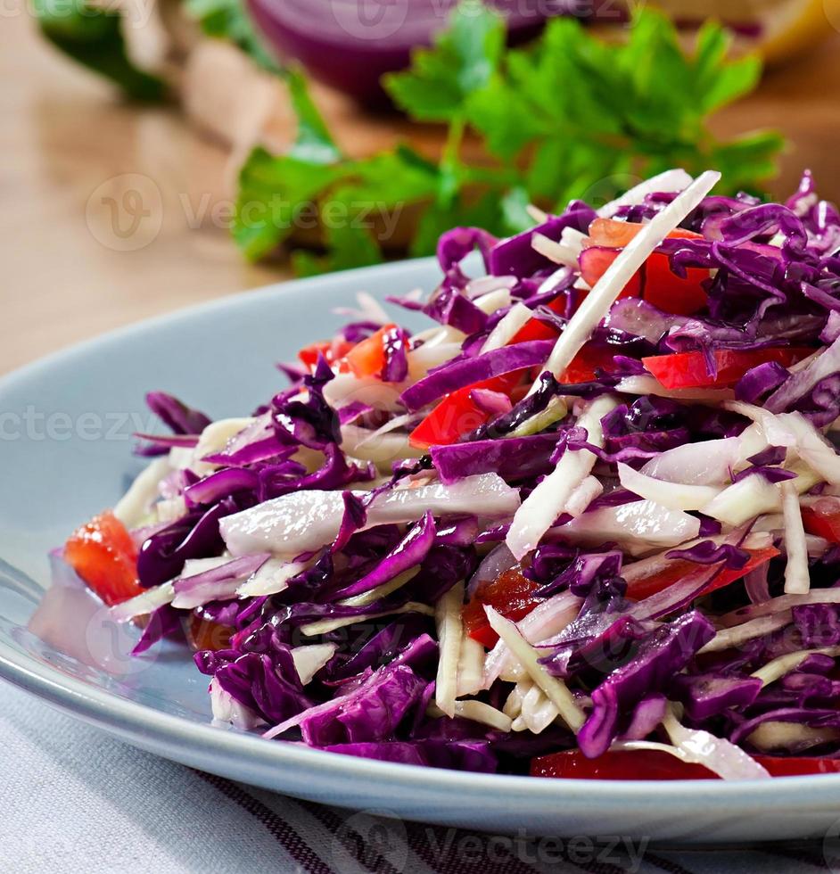 salada de repolho vermelho e branco e pimentão doce, temperada com suco de limão e azeite em tigela de madeira foto