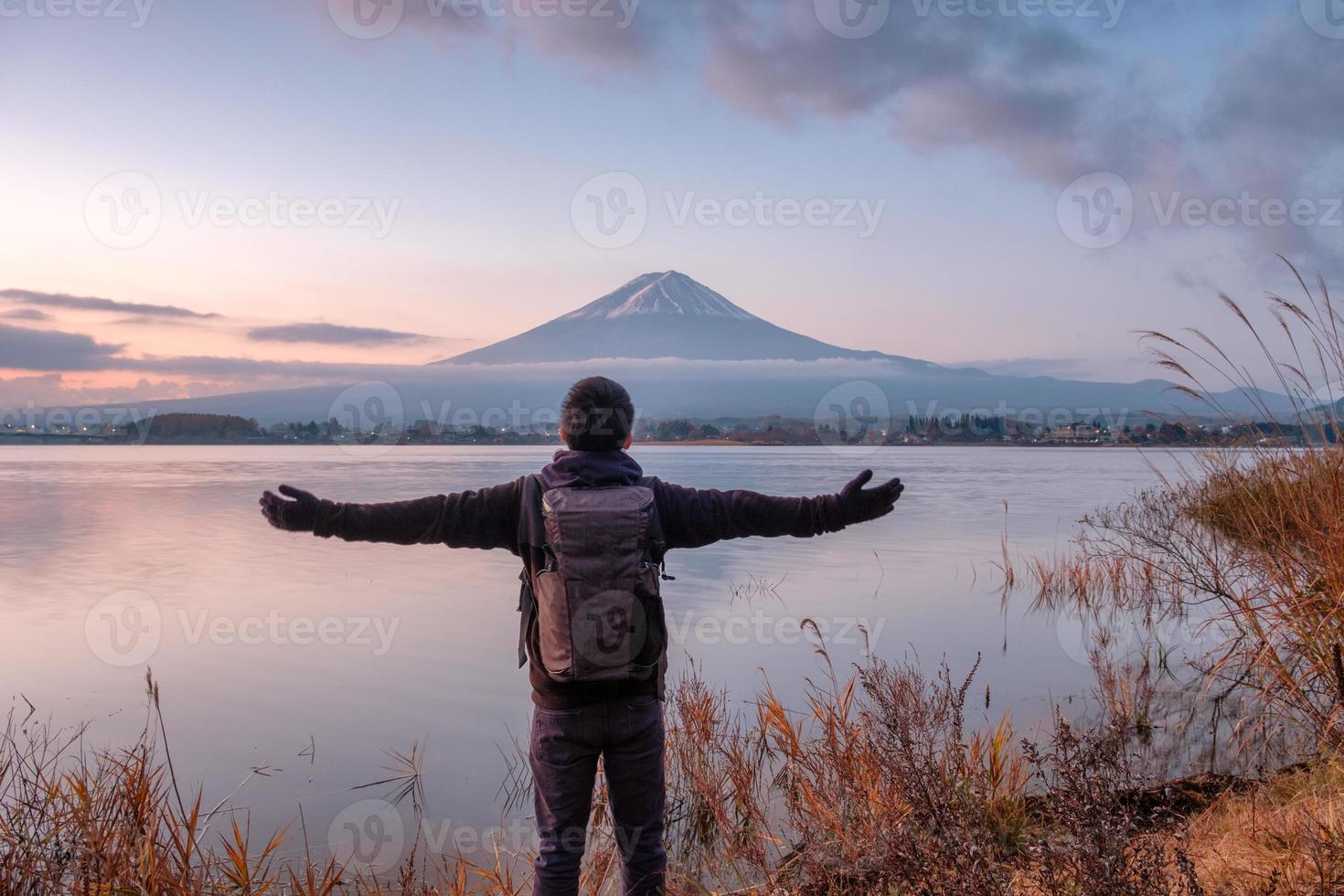 jovem asiático fica olhando o monte fuji no lago kawaguchiko ao amanhecer foto