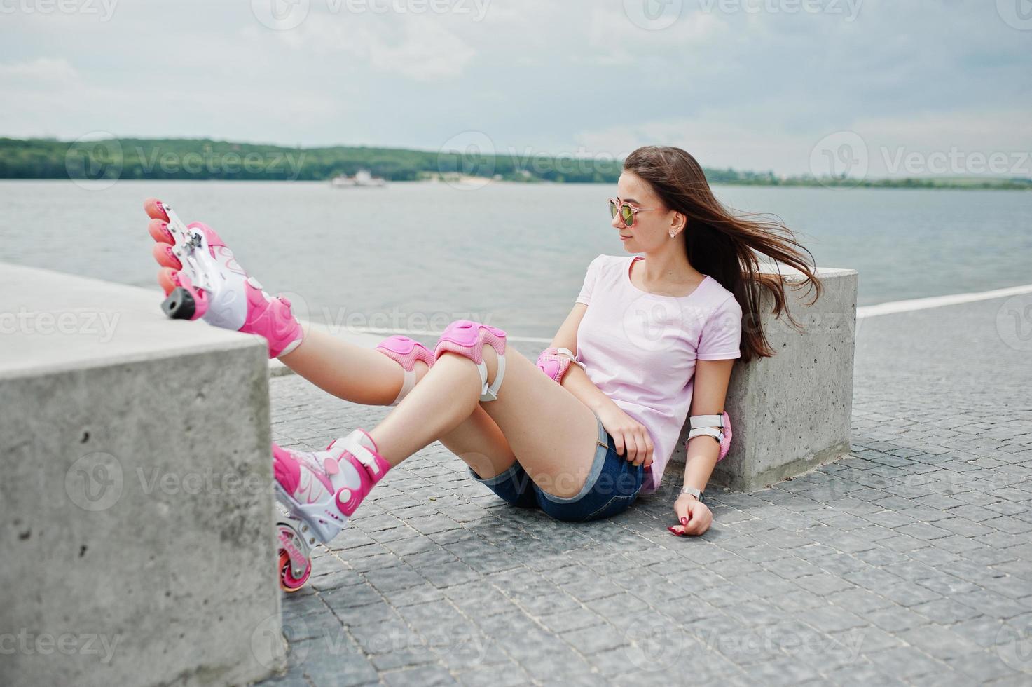 retrato de uma linda mulher sentada no chão ao lado do cubo de concreto usando patins e roupas casuais. foto