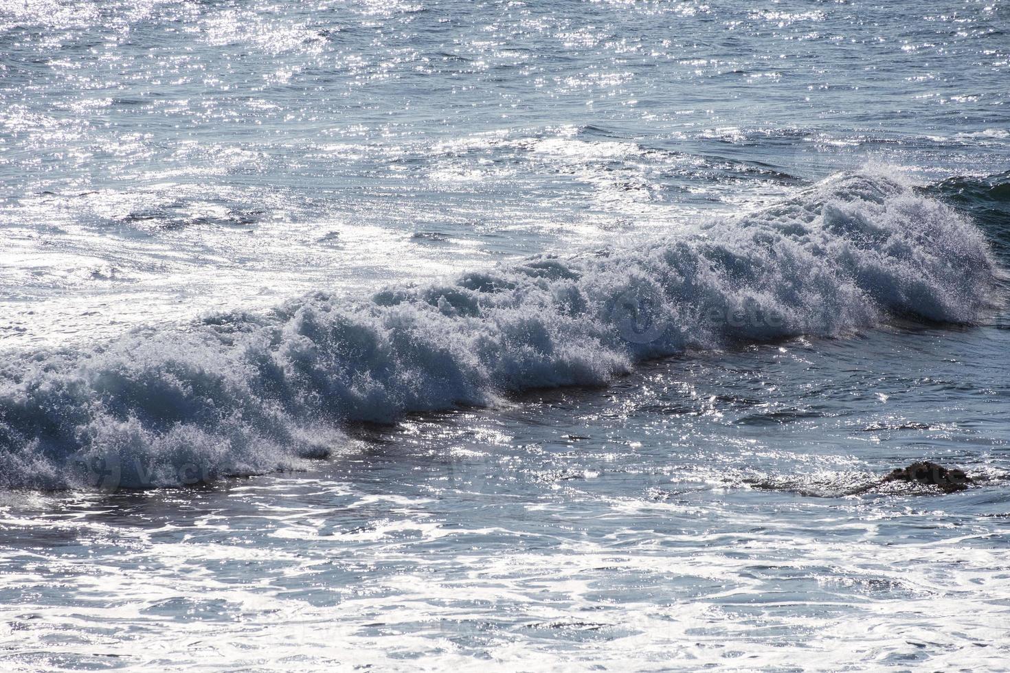 bela onda azul espirrando com espuma branca no mar tropical em ensolarado foto
