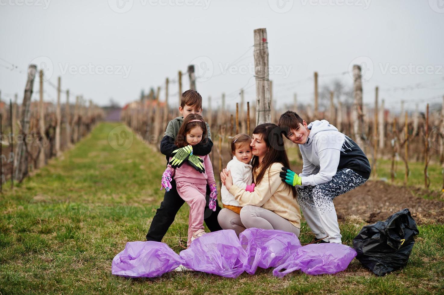 família com saco de lixo coletando lixo durante a limpeza nas vinhas. conservação ambiental e ecologia, reciclagem. foto