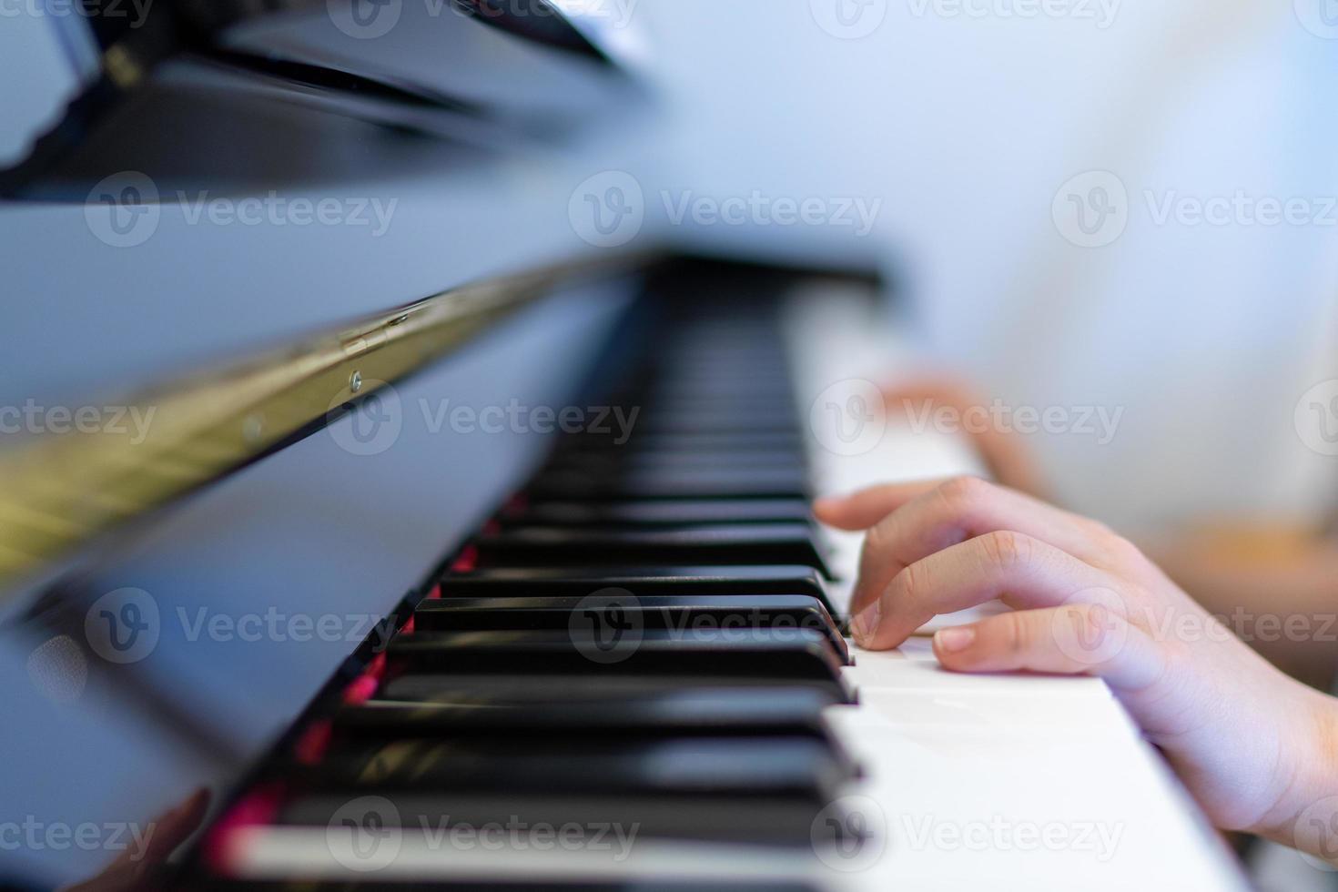 tocando piano com foco raso de mão de menino no teclado e no dedo esquerdo foto