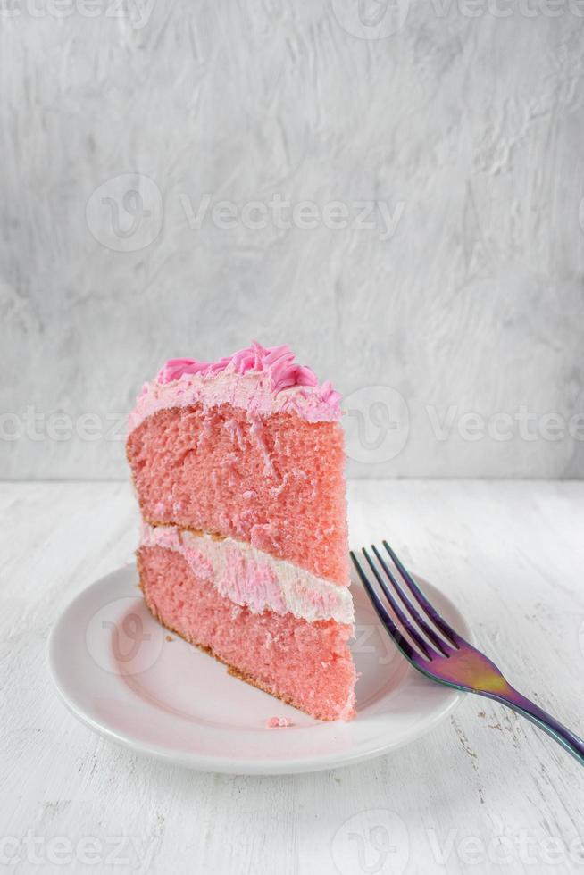 fatia fina festiva de bolo de aniversário rosa com flores de glacê e vista lateral do garfo foto