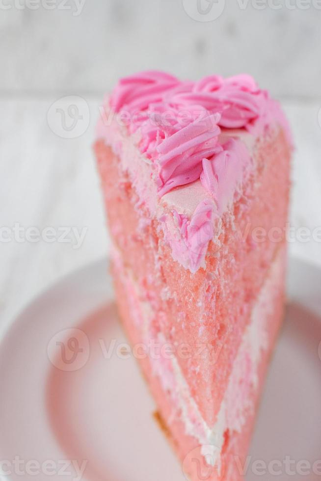 fatia fina festiva de bolo de aniversário rosa com close-up de flores de glacê foto