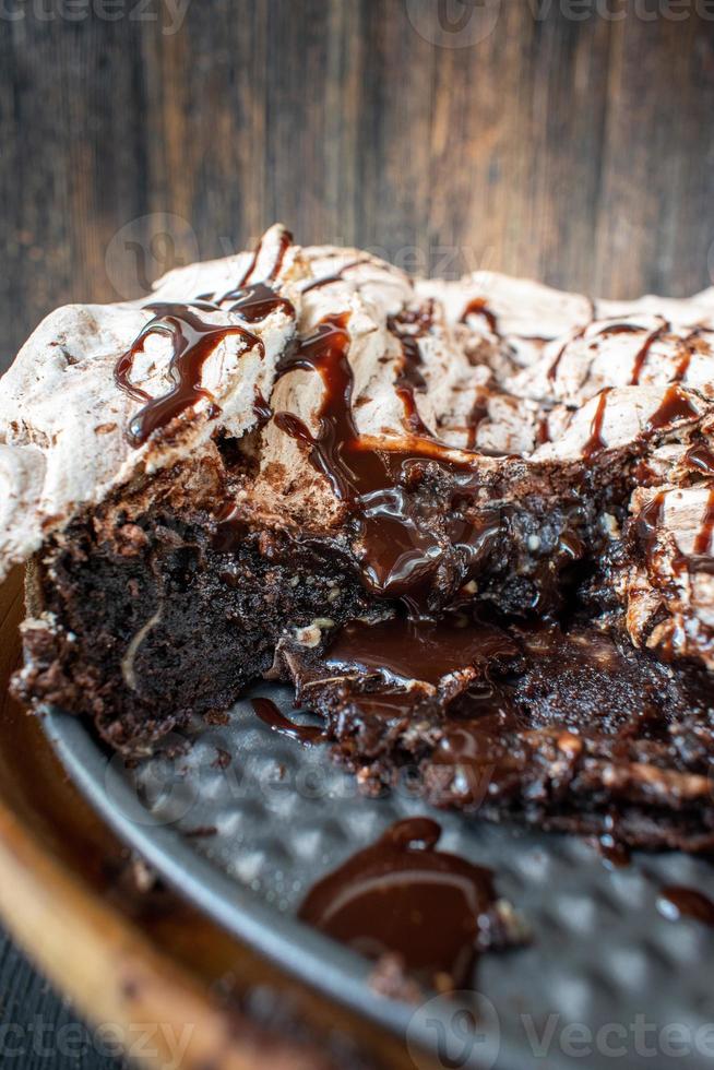 fatia de sobremesa de brownie assada coberta com merengue e redemoinhos de chocolate e calda de chocolate regada foto