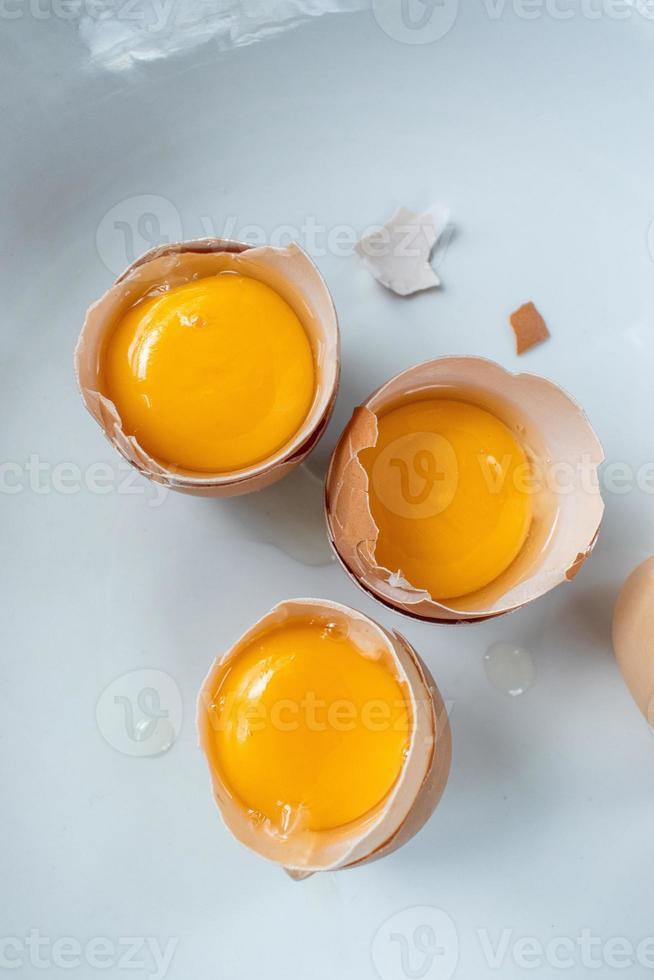grupo de gemas de ovos em cascas quebradas na postura plana de fundo branco foto