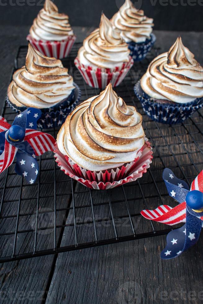 cupcakes vermelhos brancos e azuis com topos de redemoinho de merengue torrado foto