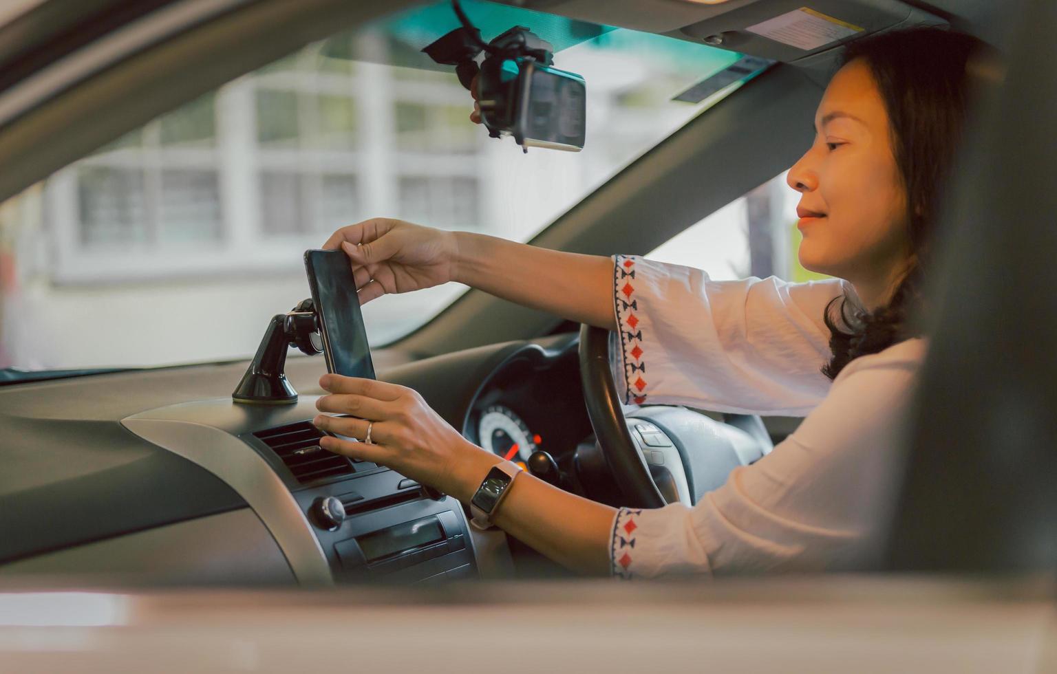 a mão do motorista da mulher ajusta o celular no suporte do suporte para direção. foto