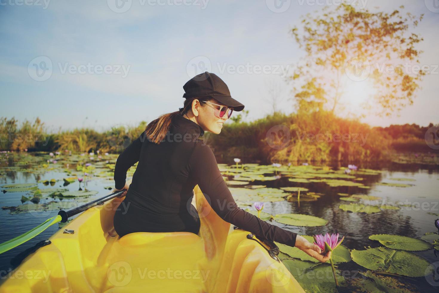 mulher velejando caiaque de mar na lagoa de flor de lótus foto