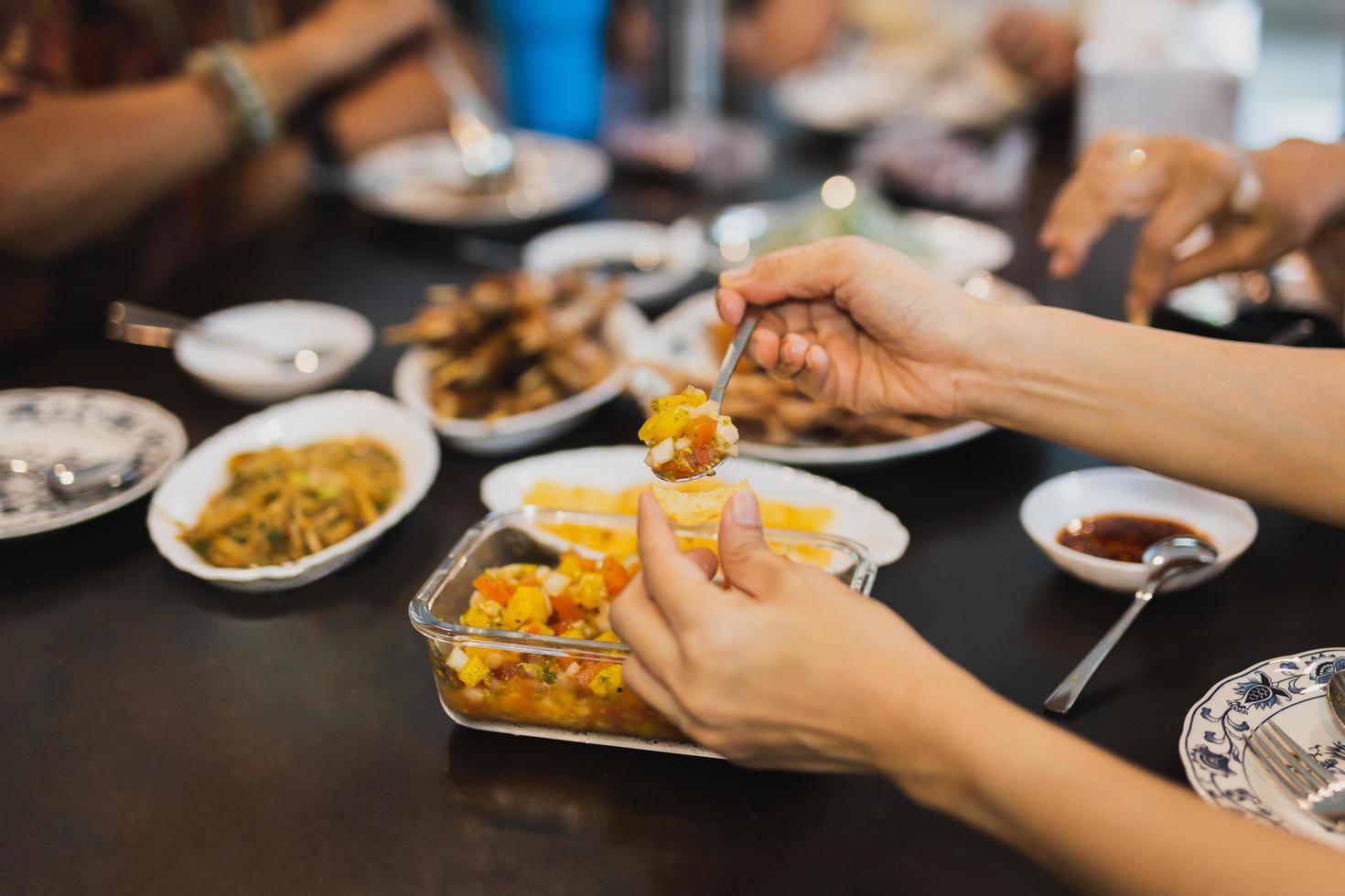 mulher comendo molho de salsa com batatas fritas com a família na hora do almoço. foto