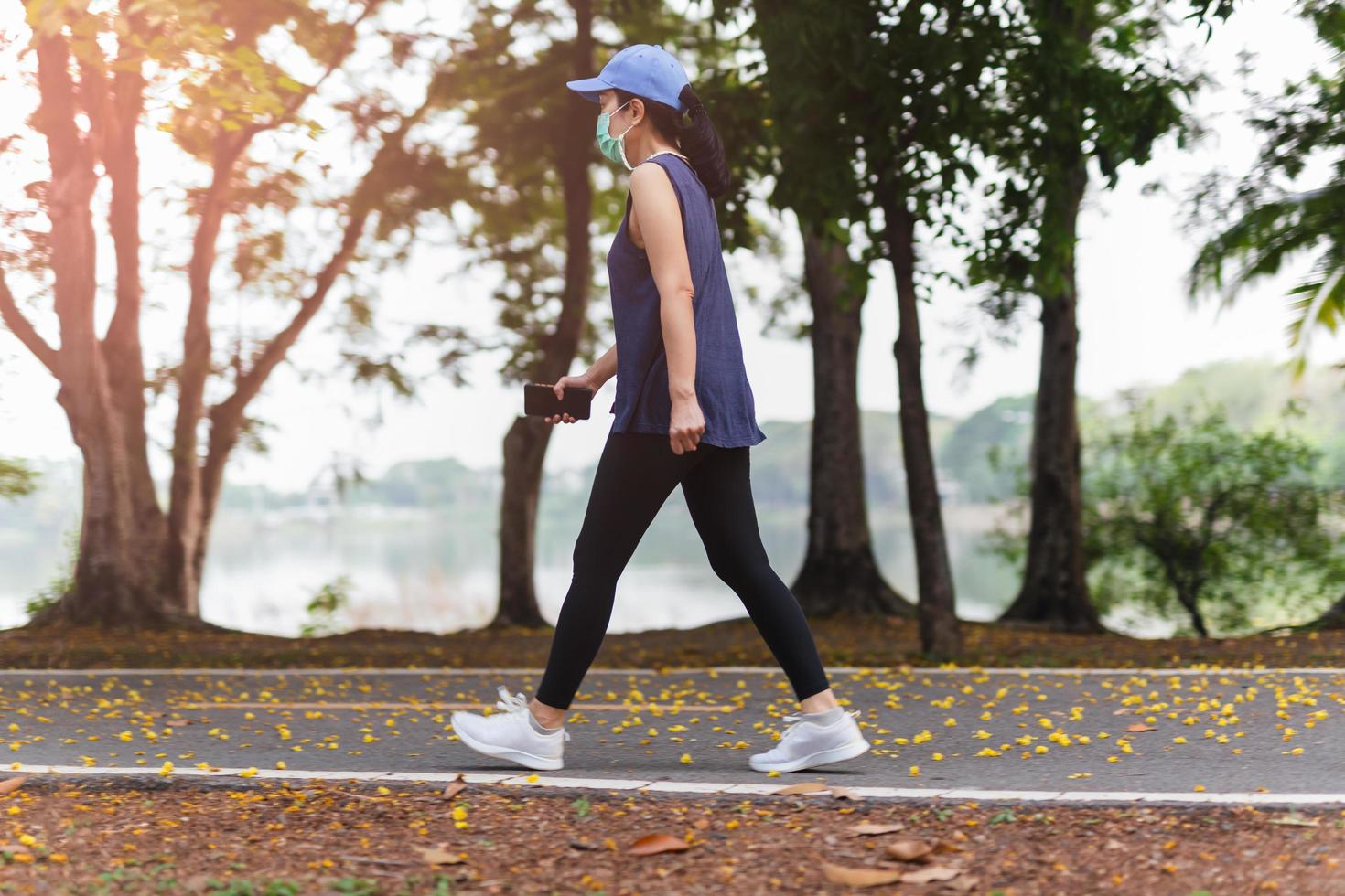 comprimento total da mulher no exercício de máscara médica andando no parque. foto