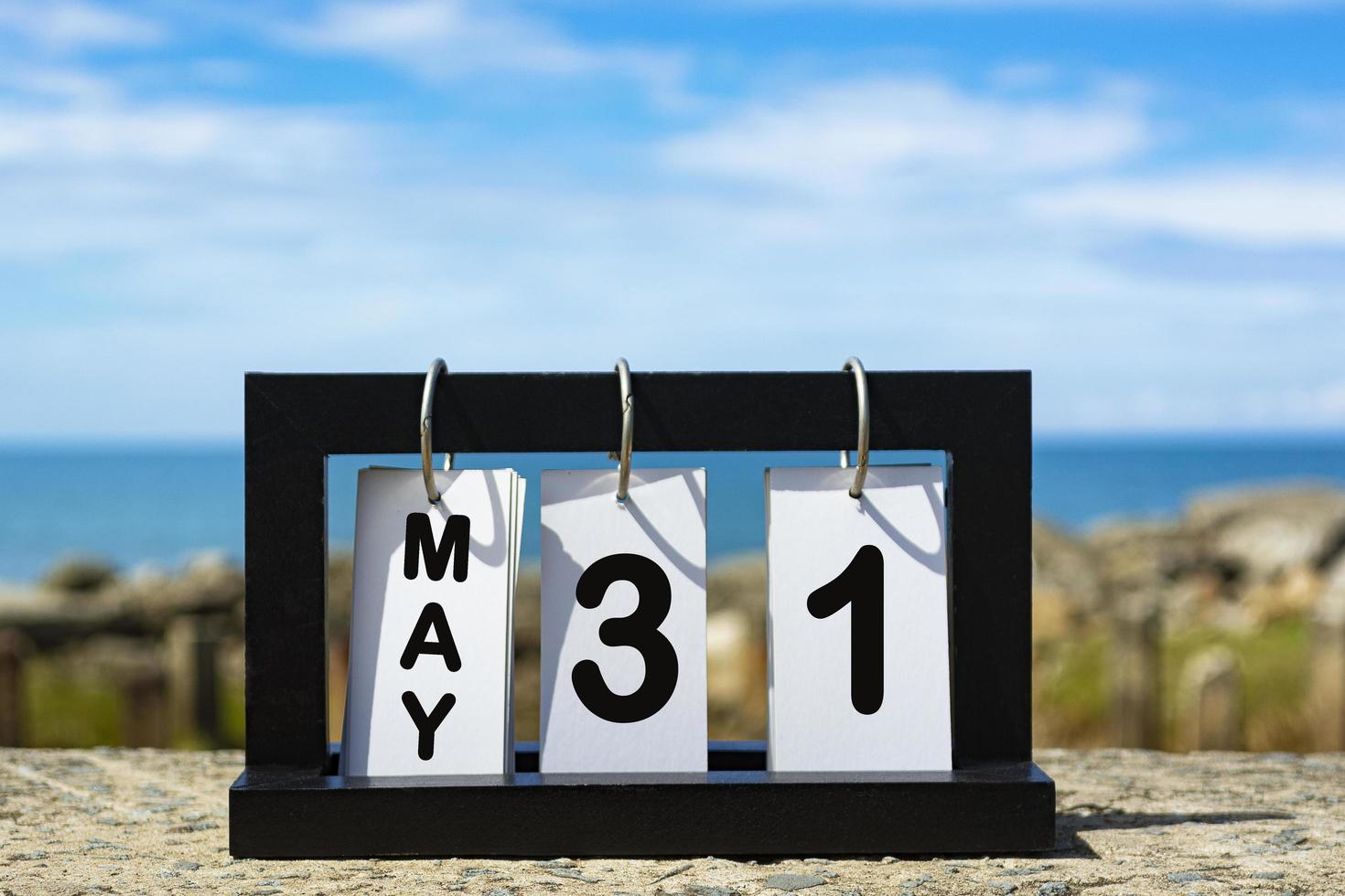 31 de maio texto de data de calendário na moldura de madeira com fundo desfocado do oceano foto