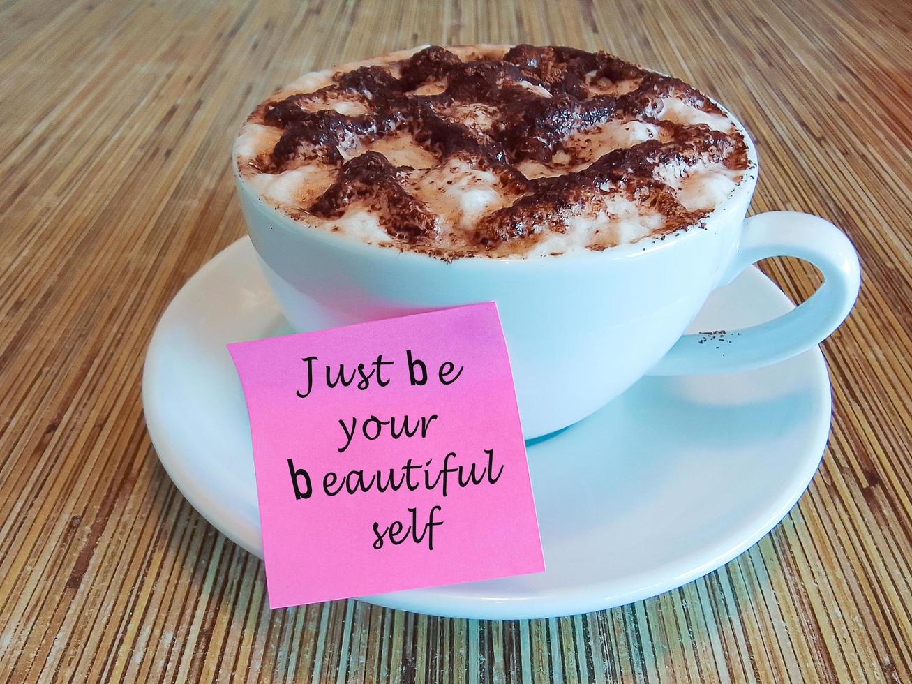 citação motivacional e inspiradora em uma nota rosa na xícara de café na mesa de madeira. foto