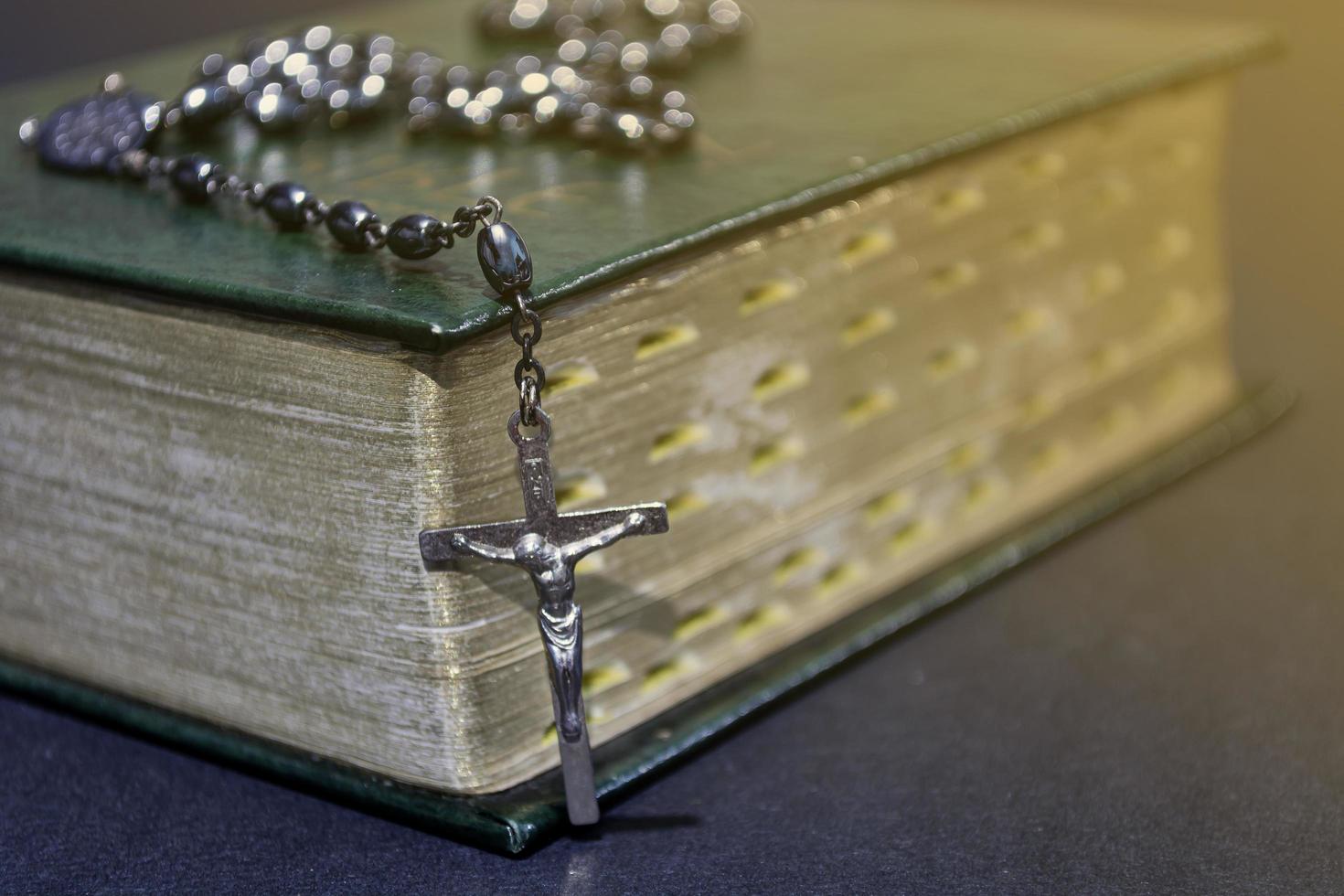 a cruz sobre a Bíblia na mesa de madeira com luz de janela, tom vintage. foto