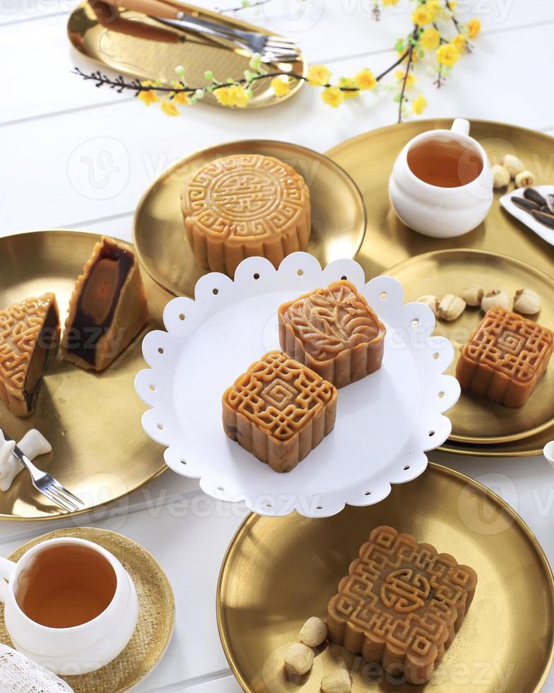 bolo de lua configuração de mesa de bolo de lua. pastelaria tradicional chinesa em forma de quadrado com xícaras de chá na mesa de vime branco. conceito de festival de meio outono com tema branco e dourado, close-up. foto