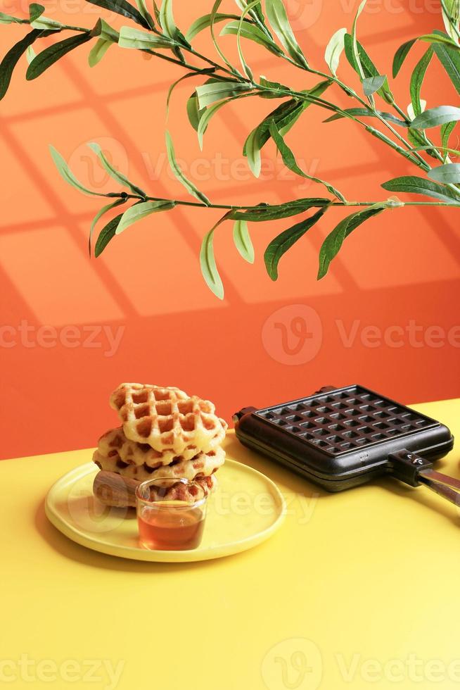 waffle de croissant empilhado na mesa amarela e fundo laranja. croffle é um bolo viral da coreia do sul. foto